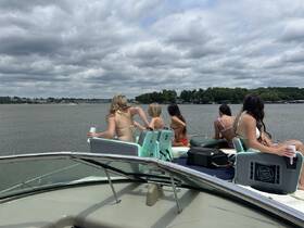 A group of friends enjoys a fun day on the water, relaxing on a boat with drinks in hand — perfect for summer outings and celebrations.