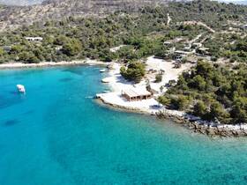 A stunning aerial view of a serene beach with turquoise waters and a cozy beachside structure, perfect for relaxation and enjoying the natural beauty of the coastline.