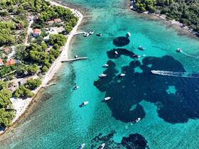 A stunning aerial view of a picturesque coastline with multiple boats navigating through crystal-clear turquoise waters, showcasing the beauty of a serene summer day.