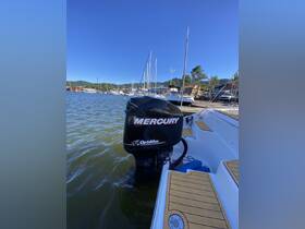 Close-up of a Mercury outboard motor on a boat at the dock, showcasing the vessel's features against a clear blue sky.