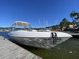 A sleek speedboat named 'Manira II' docked at a marina, showcasing its elegant design against a clear blue sky.