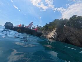Two individuals enjoy a sunny day on a boat near a scenic coastline, capturing the essence of adventure on the water.