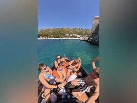 A lively group enjoys drinks and fun on a boat, surrounded by stunning coastal scenery — perfect for summer adventures and celebrations on the water.