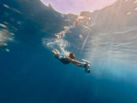 A swimmer explores the vibrant underwater world while snorkeling, showcasing the beauty of marine life in crystal-clear waters.
