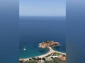 A stunning aerial view of a picturesque island with red-roofed buildings surrounded by clear blue waters, perfect for showcasing coastal beauty and sailing adventures.