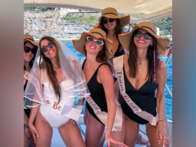 A lively group of friends celebrates a bachelorette party on a boat, showcasing fun and camaraderie against a stunning coastal backdrop.