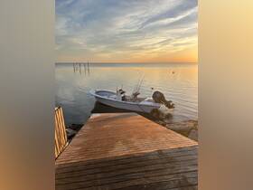 A serene view of a speedboat docked at sunset, reflecting the calm waters — perfect for fishing trips or leisurely outings.