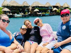 A joyful group of family members enjoys a sunny day on a boat, surrounded by beautiful waterfront accommodations — perfect for memorable vacations and family bonding.