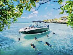 A group of snorkelers explores the vibrant underwater world near a sleek boat in crystal-clear waters, perfect for adventure seekers and marine enthusiasts.
