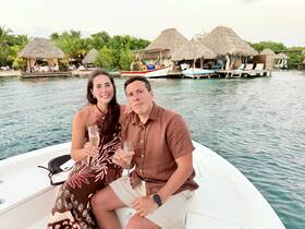 A couple enjoys a romantic moment on a boat, toasting with champagne against a picturesque waterfront backdrop — perfect for special celebrations or intimate getaways.