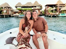 A couple enjoys cocktails on the deck of a boat, surrounded by stunning waterfront accommodations — perfect for romantic getaways or special celebrations.