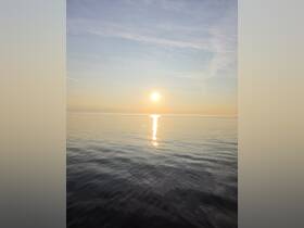 A serene view of the sun setting over calm waters, creating a peaceful atmosphere perfect for relaxation.