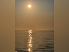 A serene view of the sun reflecting on calm waters, creating a tranquil atmosphere perfect for sunset cruises.