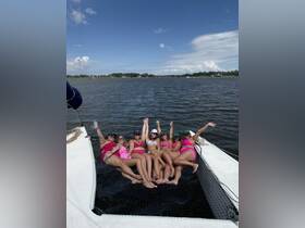 A lively group of friends enjoys a fun day on the water, lounging on the netting of a pontoon boat, perfect for summer celebrations and memorable outings.