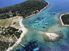 A stunning aerial view of a serene coastal landscape featuring crystal-clear waters, sandy beaches, and several boats anchored near a picturesque island — perfect for exploring and relaxing in nature.