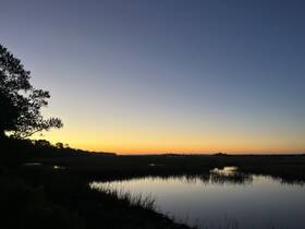 A serene sunset over a marshland, capturing the tranquil beauty of nature. Ideal for those seeking peaceful landscapes.