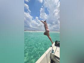A woman joyfully jumps into the crystal-clear waters, ready for a snorkeling adventure — a perfect moment capturing the thrill of summer fun on the beach.