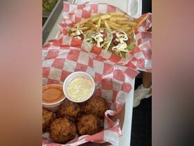 A delicious spread featuring tacos, fries, and dipping sauces, perfect for enjoying on a boat trip or at a beachside eatery.