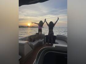 A joyful moment as a woman and a child celebrate the sunset on a boat, capturing the essence of family fun and adventure on the water.