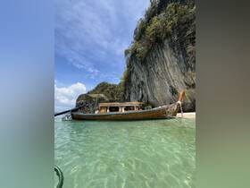 A beautifully crafted wooden boat docked in crystal-clear waters, framed by stunning rocky cliffs and a bright blue sky — perfect for exploring tropical destinations.