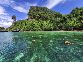 A vibrant scene of snorkelers exploring crystal-clear waters near a lush island, showcasing the beauty of marine life and the joy of outdoor adventures.