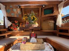 A beautifully decorated interior of a boat featuring vibrant flowers and a cozy seating area, perfect for relaxing while enjoying snacks on the water.