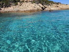 A serene view of crystal-clear waters and rocky shoreline, perfect for showcasing beautiful coastal destinations.