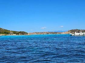 A scenic view of a yacht cruising through crystal-clear turquoise waters, surrounded by picturesque coastline and lush greenery, perfect for a relaxing day on the water.