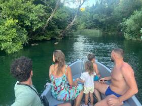 A family enjoys a serene boating experience on a tranquil river, observing ducks amidst lush greenery — perfect for nature lovers and family outings.