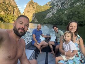 A joyful family enjoys a boat ride on a serene river, surrounded by stunning cliffs and greenery — perfect for creating lasting memories on the water.