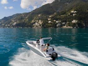 A couple enjoys a scenic ride on a boat along a stunning coastline, showcasing the beauty of the landscape and the thrill of being on the water.