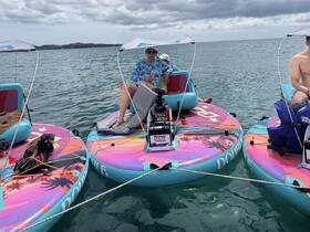 A group enjoys a fun day on colorful paddleboards, soaking up the sun and engaging in water activities — perfect for a memorable outing on the water.