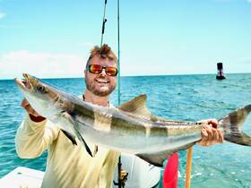 A proud angler displays his impressive catch while fishing in the ocean, showcasing the thrill of a successful day on the water.