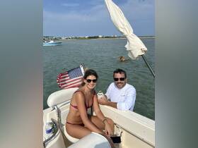 A fun day on the water with friends, enjoying drinks and laughter aboard a boat, with a playful dog swimming nearby.