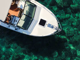 Aerial view of a sleek boat navigating through crystal-clear waters, showcasing its elegant design and the vibrant underwater scenery.