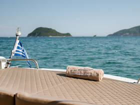 A luxurious towel rests on the deck of a boat, with a stunning view of the sea and distant islands, perfect for a relaxing day on the water.