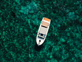 A stunning aerial view of a boat gliding over crystal-clear waters, showcasing the vibrant underwater scenery — perfect for exploring the beauty of marine life.