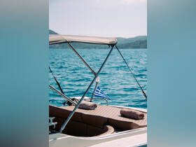 A close-up view of the interior seating area of a boat, featuring plush cushions and a Greek flag, perfect for relaxing on the water.