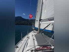 A sailor navigates a beautiful yacht against a backdrop of lush mountains and clear blue waters, showcasing the thrill of sailing adventures.