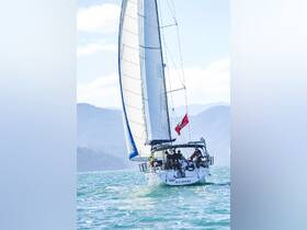 A sailboat named M.C. DAUD glides through turquoise waters with a group of people on board, showcasing the joy of sailing adventures.