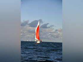 A stunning sailboat with a vibrant red sail glides through the waves, showcasing the beauty of sailing on open waters.