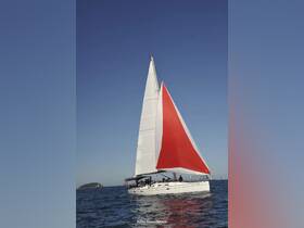 A beautiful sailboat with a striking red and white sail glides through the water, showcasing the perfect day for sailing adventures.