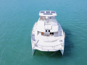 Aerial view of a sleek catamaran cruising through clear turquoise waters, showcasing its modern design and spacious layout, perfect for luxury charters.