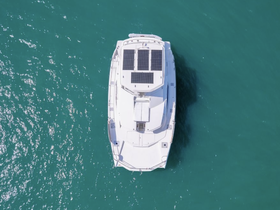 Aerial view of a sleek boat equipped with solar panels, gliding through clear turquoise waters — ideal for eco-friendly adventures.
