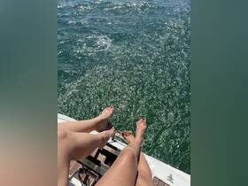 Two pairs of feet dangle over the side of a boat, enjoying the sparkling water below — a perfect moment of relaxation on a sunny day.