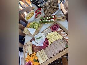 A beautifully arranged charcuterie board featuring an assortment of cheeses, meats, and fresh grapes, perfect for enjoying snacks on a boat trip.