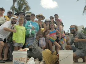 A vibrant group photo capturing a joyful celebration at the beach, showcasing families and friends enjoying their time together in the sun.