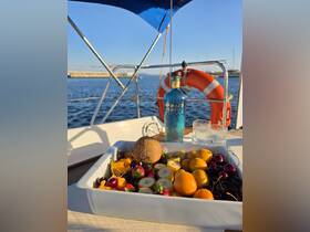 A beautifully arranged platter of fresh fruits alongside a bottle of Mermaid Gin, perfect for enjoying a refreshing drink while sailing on the water.