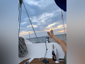 A serene moment aboard a sailboat at sunset, featuring a glass of champagne and relaxed feet, perfect for unwinding on the water.
