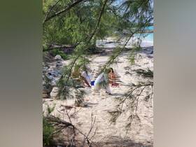 A group enjoys a serene beach setting, surrounded by nature and building stone sculptures — a perfect moment of relaxation and creativity by the shore.